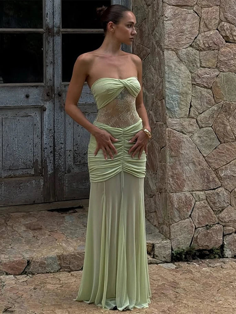 Woman in a light green strapless dress standing against a stone wall.