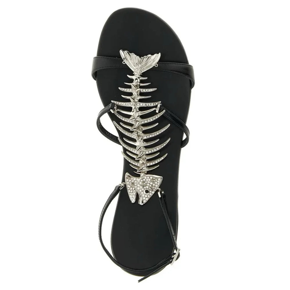 Top view of a black flat sandal with a silver rhinestone fishbone embellishment
