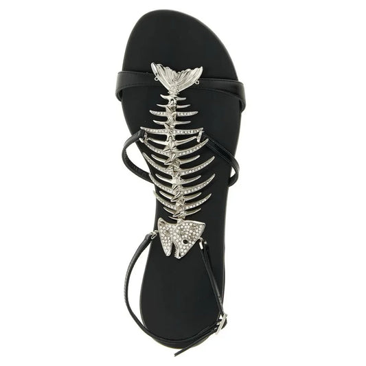 Top view of a black flat sandal with a silver rhinestone fishbone embellishment