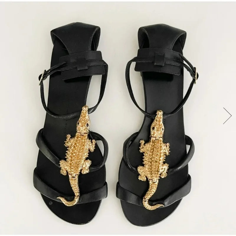 Black flat sandals with gold alligator embellishment