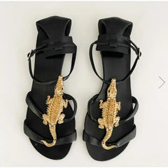 Black flat sandals with gold alligator embellishment