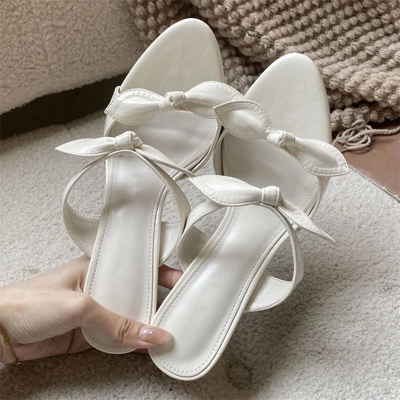 Cream pointed toe mules with a delicate bow detail