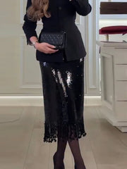 Person wearing a black sequin skirt with a matching blazer indoors.