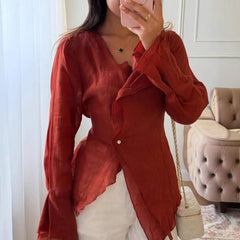 Person wearing a red shirt in a room with a chair and table.