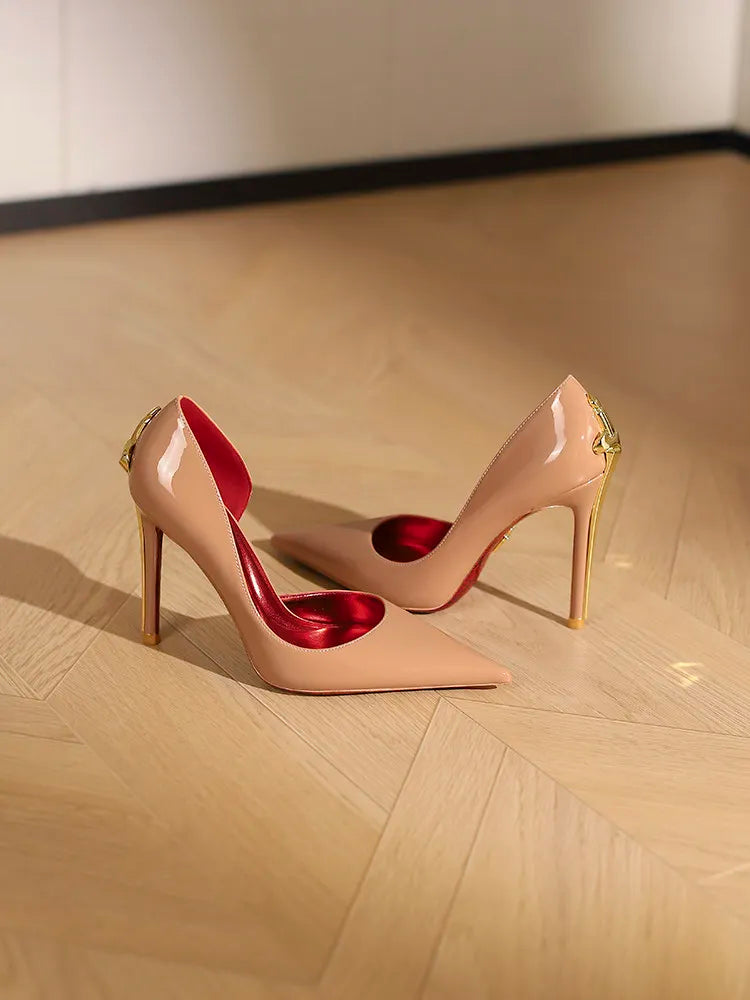 Pair of high-heeled shoes with red insoles on a wooden floor.