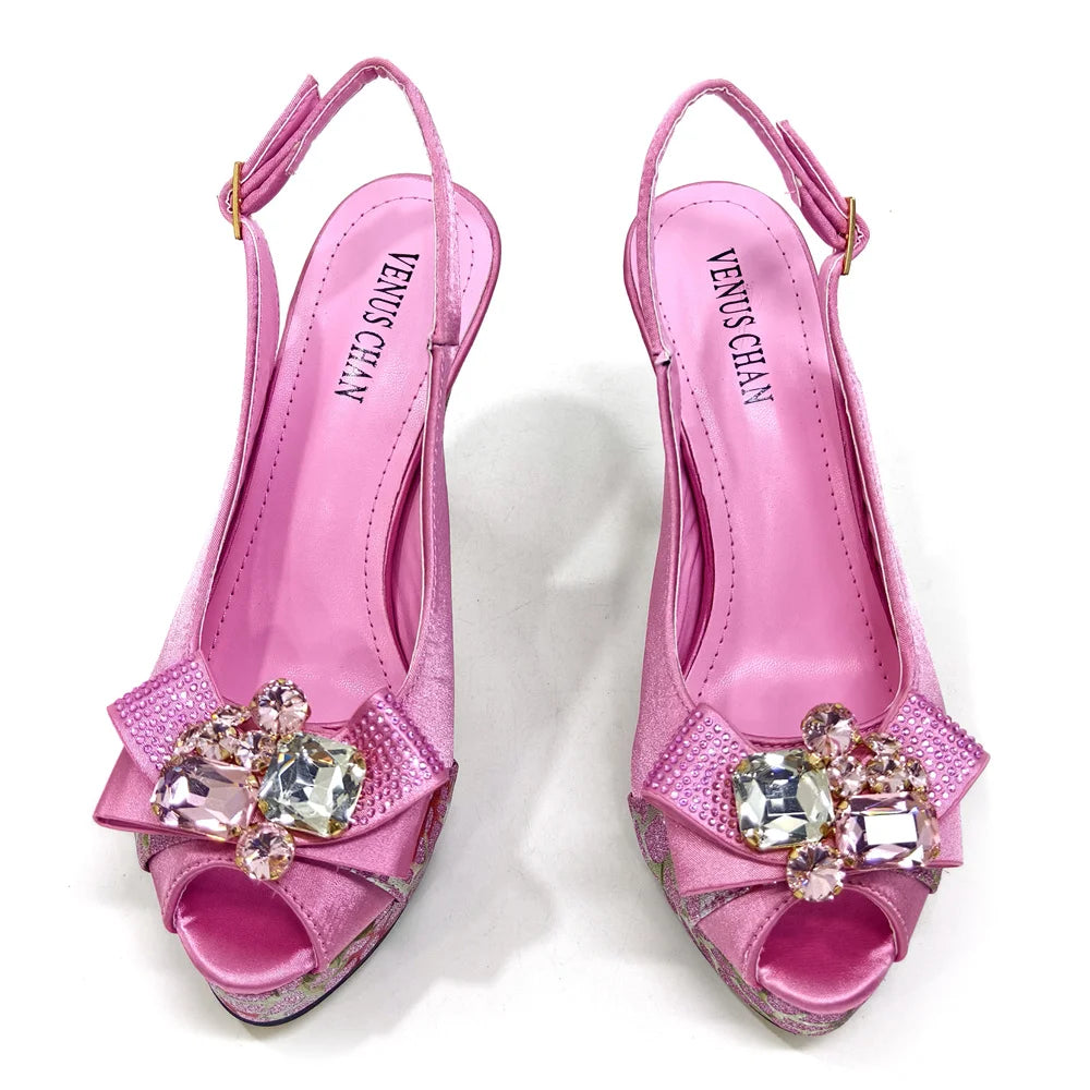 Pink high-heeled shoes with crystal embellishments on a white background