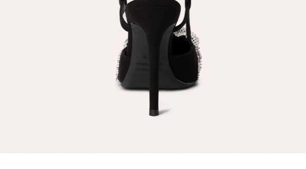 Black high-heeled shoe with studded details on a white background