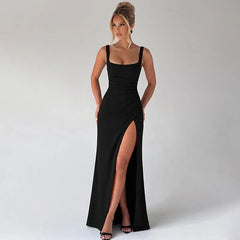 Woman wearing a black evening gown with a high slit on a plain background