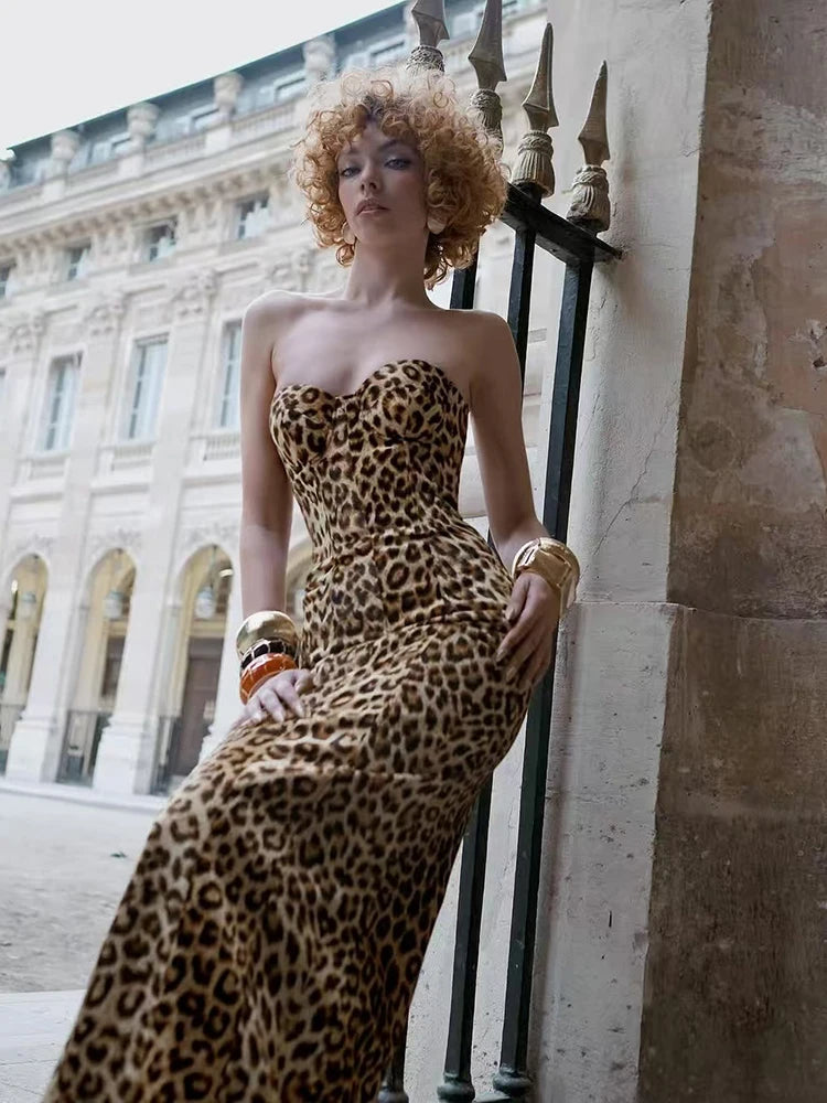 Woman in a leopard print dress standing against a stone building.