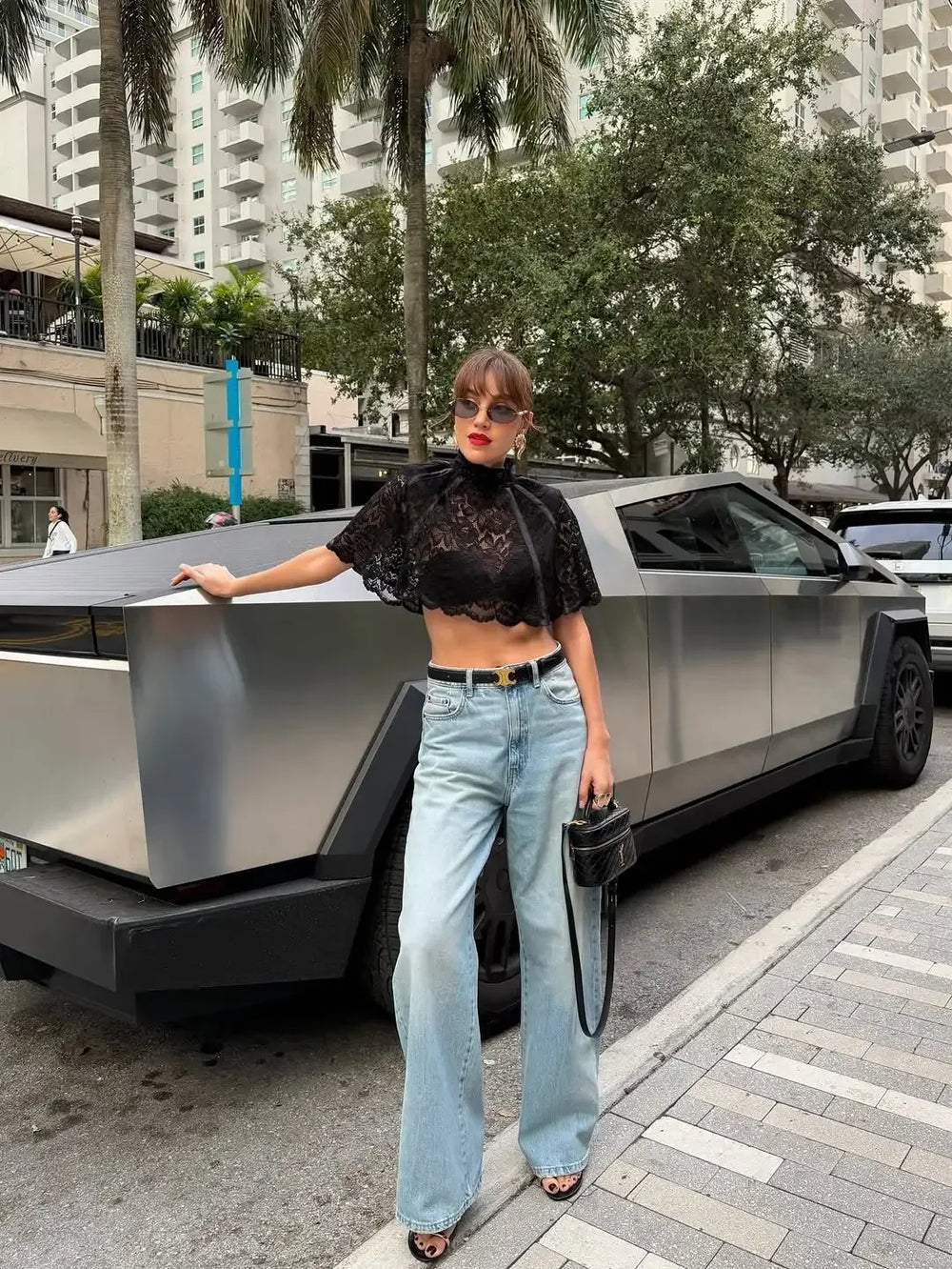 Woman posing next to a futuristic car on a city street