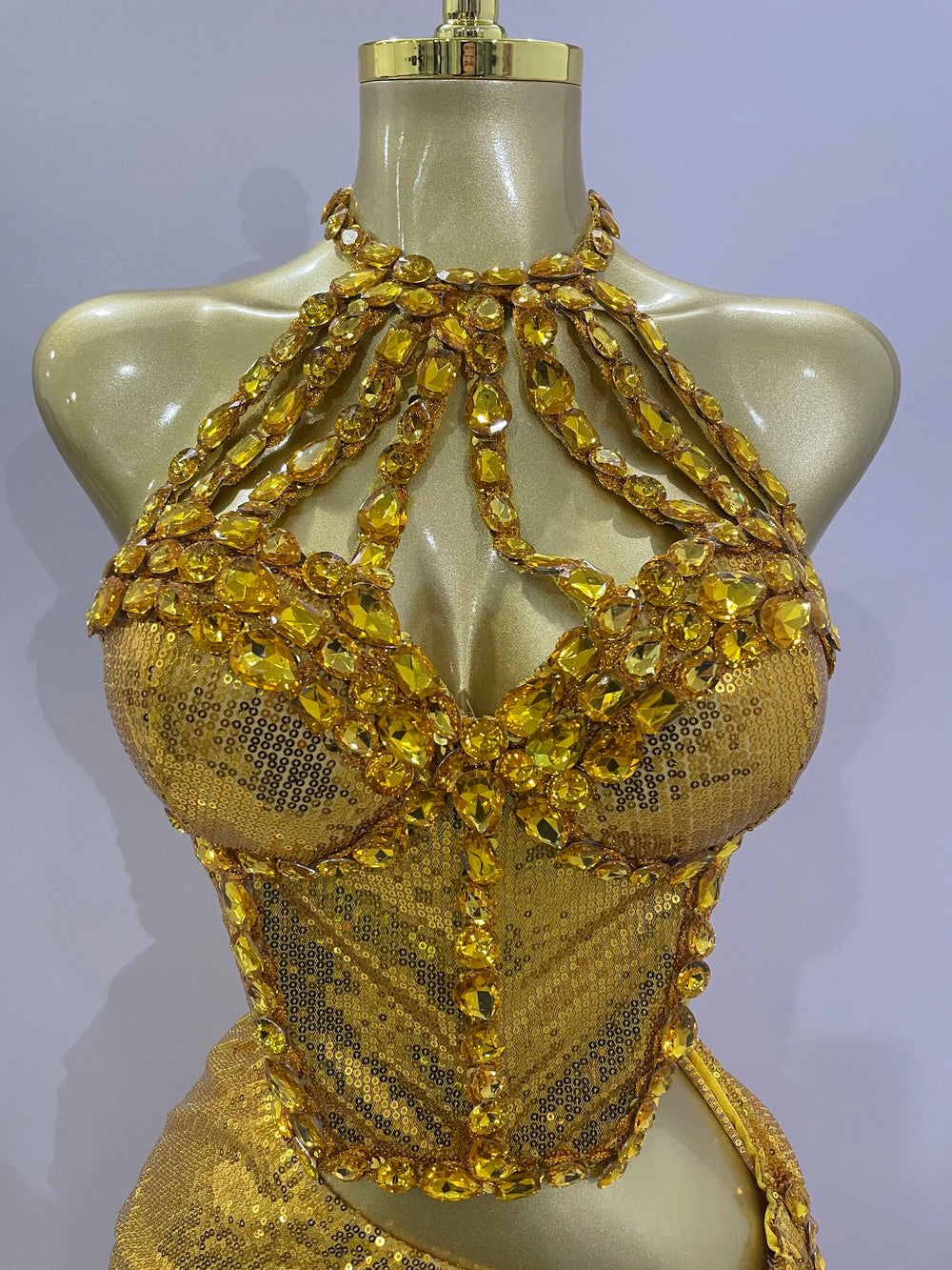 Gold beaded top on a mannequin against a plain background