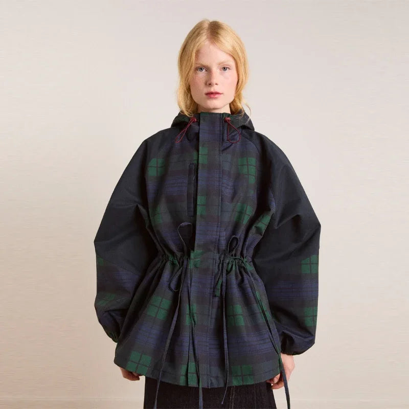 Person wearing a dark plaid coat on a plain background