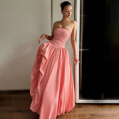 Woman in a pink strapless gown standing in a room with a mirror.