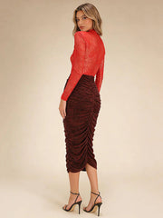 Woman wearing a red top and brown ruched skirt on a beige background
