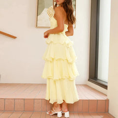 Woman wearing a yellow ruffled dress standing on a tiled floor.