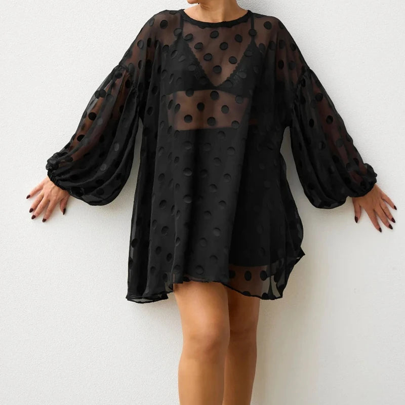 Black polka dot dress with sheer overlay on a white background