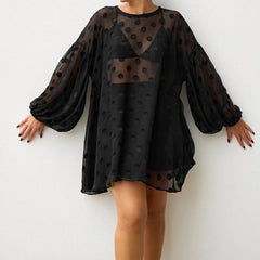 Black polka dot dress with sheer overlay on a white background
