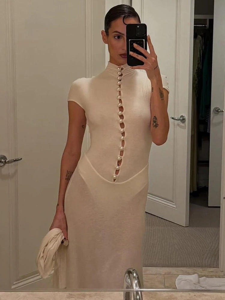 Woman taking a mirror selfie wearing a beige dress with button details.