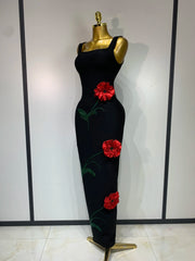 Side view of a black body-skimming gown adorned with red floral appliqués.