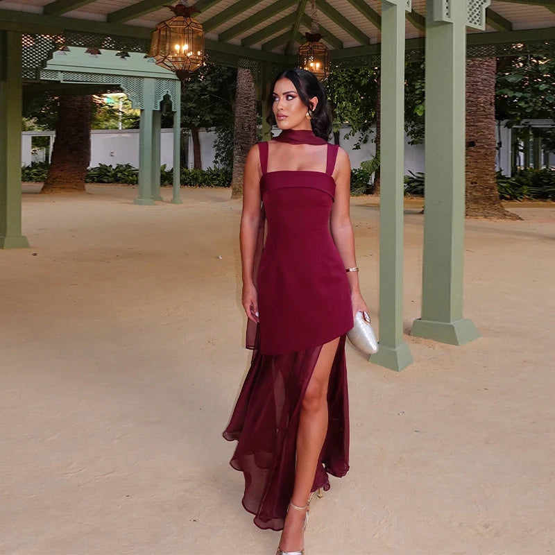 Woman in a burgundy dress standing outdoors under a green gazebo.