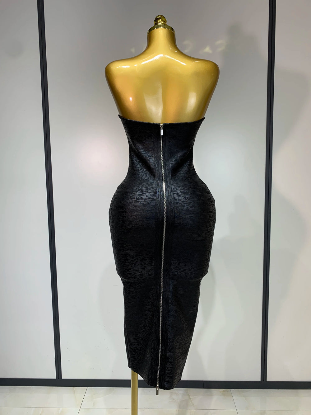 Black dress on a mannequin against a plain background