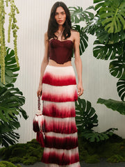 Woman in a red and white dress standing among green leaves
