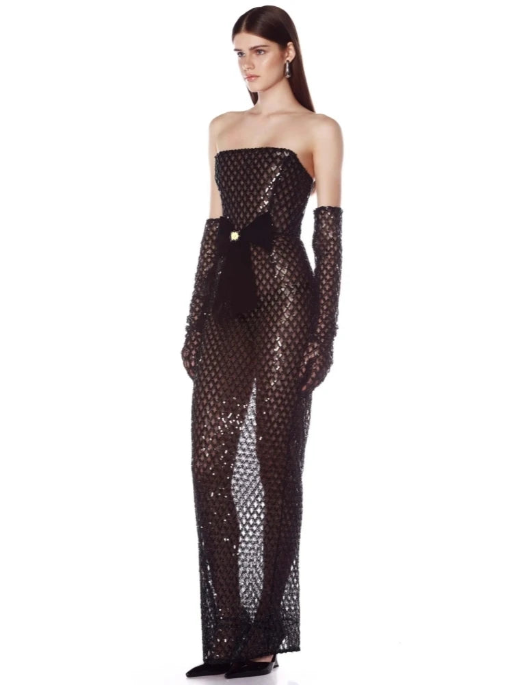 Woman wearing a black strapless sequin gown with long gloves on a white background