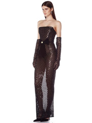 Woman wearing a black strapless sequin gown with long gloves on a white background