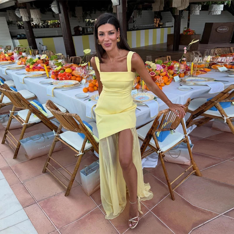 Woman in a yellow dress standing in front of a decorated outdoor dining area.