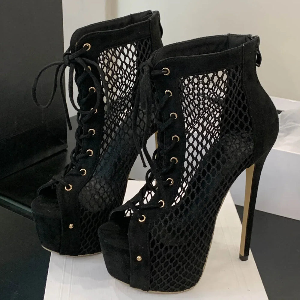 Black suede high-heeled boots with mesh design on a white surface.