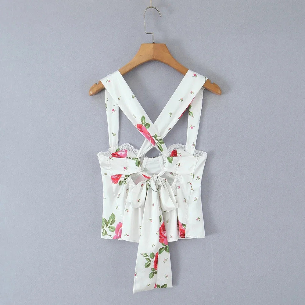 Floral-patterned dress with suspenders on a wooden hanger against a gray background