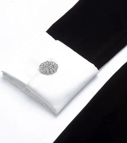 Silver cufflinks on a white box with black fabric in the background