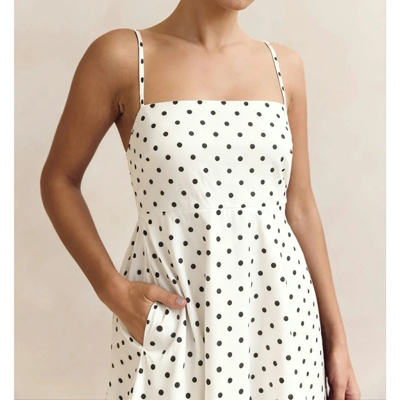 White dress with black polka dots worn by a person on a beige background