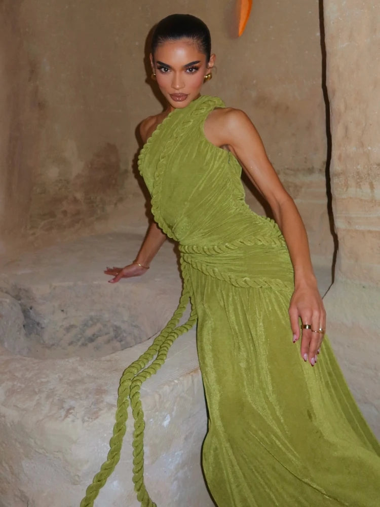 Woman in a green dress standing against a textured wall.