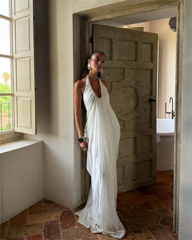 Woman in a white dress standing in a room with a wooden door and window.