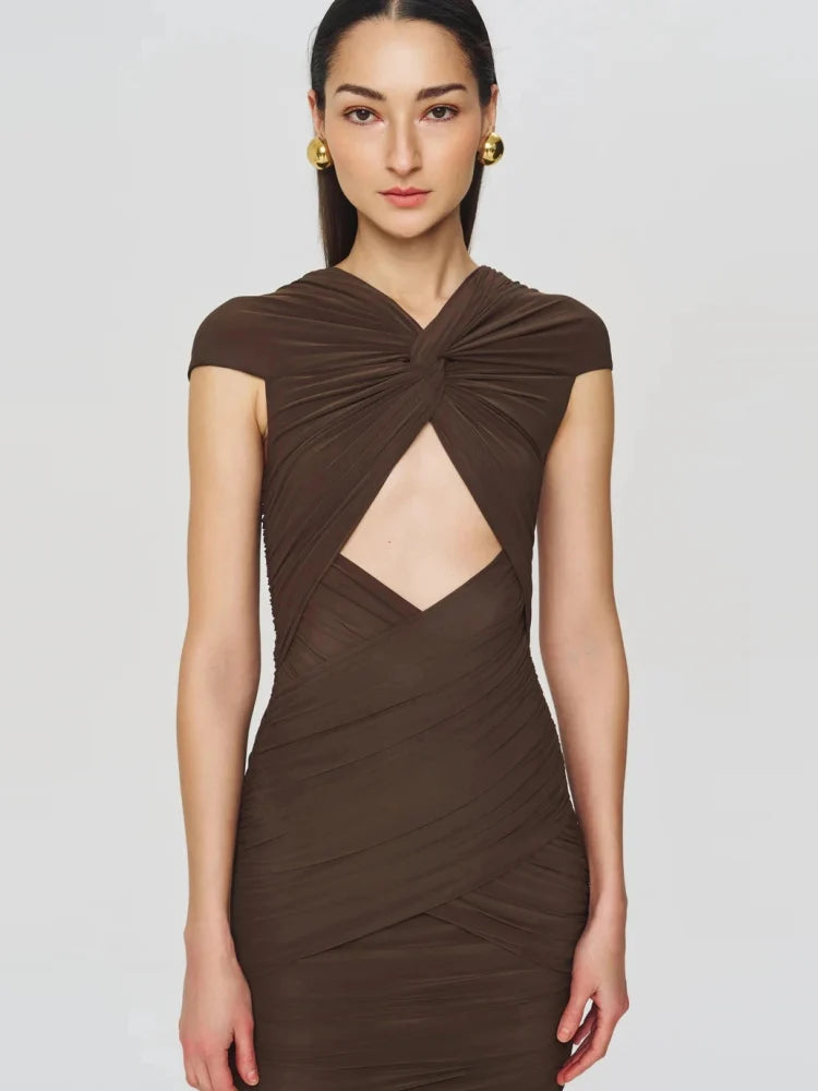 Woman wearing a brown dress with cut-out design on a plain background