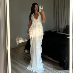 Woman in a white dress taking a mirror selfie in a room.
