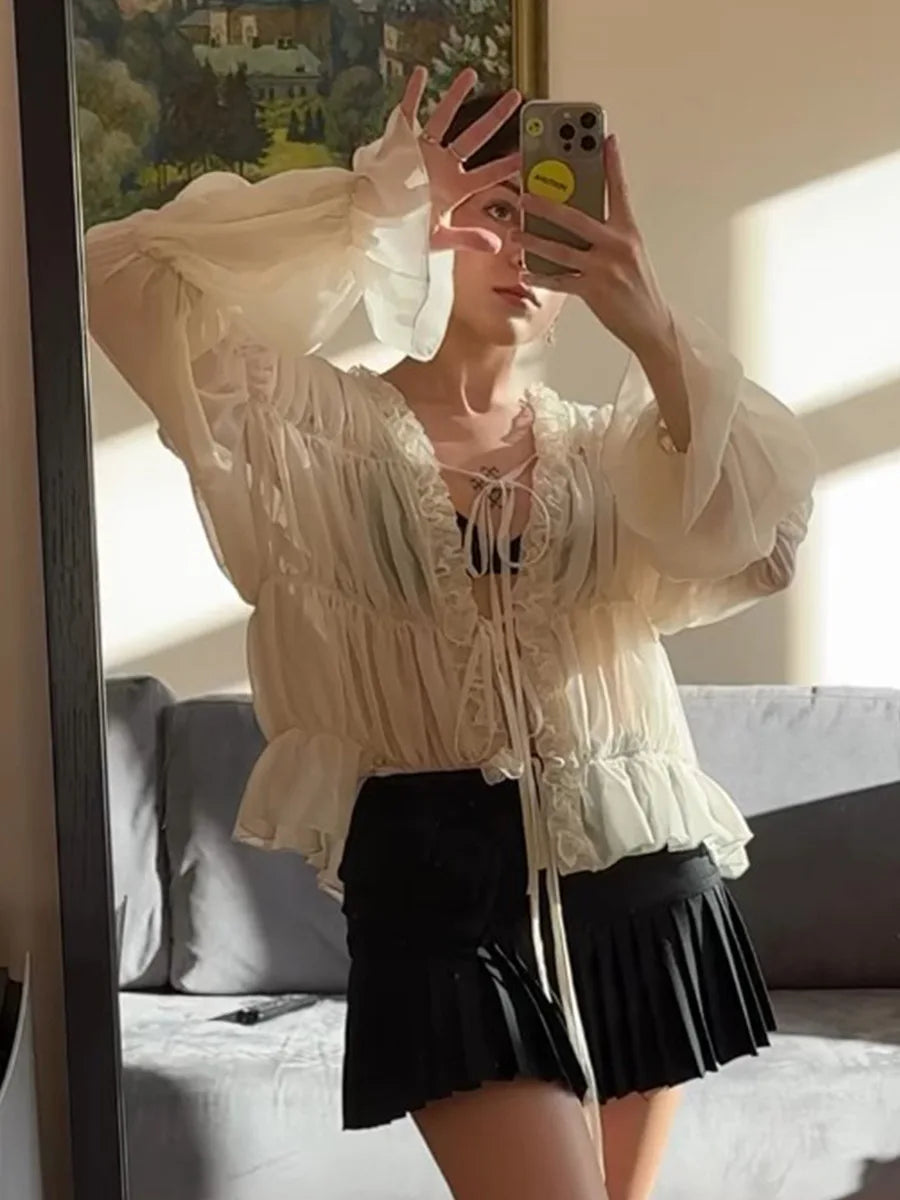 Person wearing a white lace top and black skirt taking a mirror selfie.