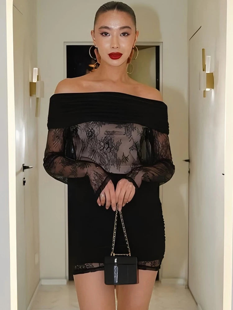 Woman wearing a black off-shoulder dress with sheer overlay in a room.