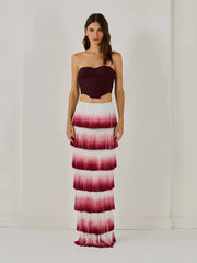 Woman wearing a strapless top and ombre pink to white skirt on a plain background