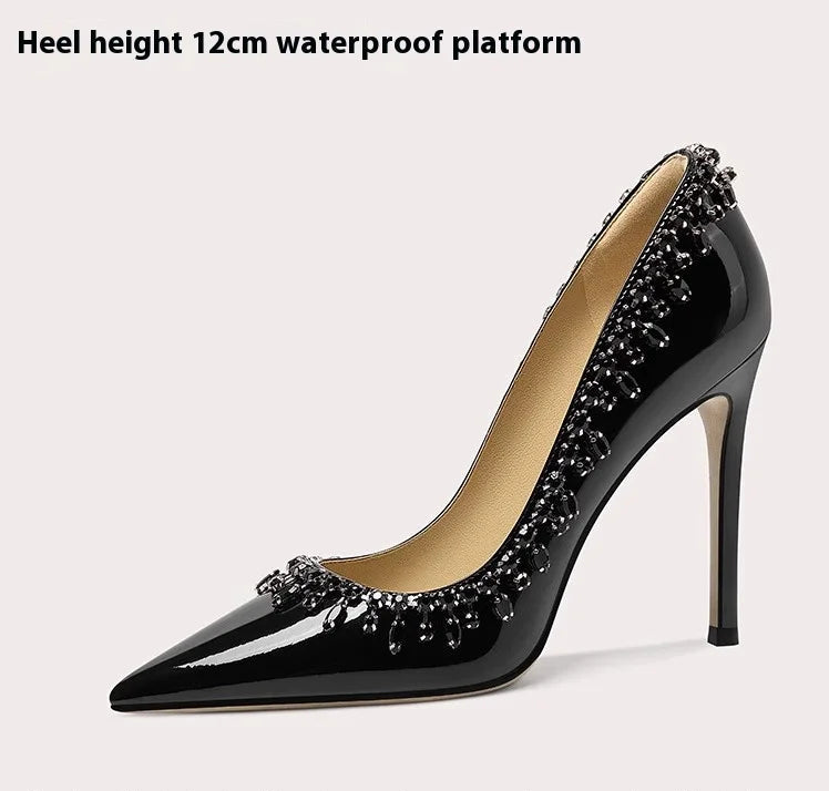 Black high-heeled shoe with embellishments on a light beige background