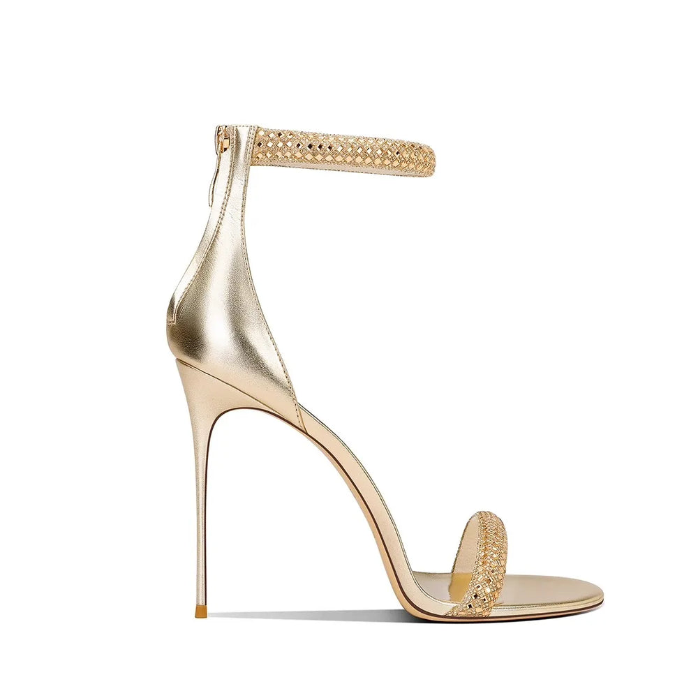 Gold high-heeled sandal with embellishments on a white background