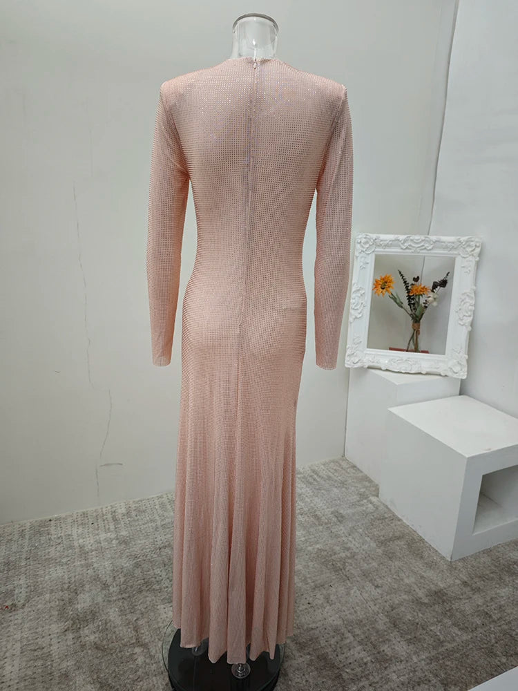 Mannequin wearing a long-sleeve, high-neck dress in a minimalistic room with a mirror and flowers.