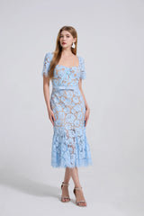 Woman wearing a light blue floral lace dress on a white background