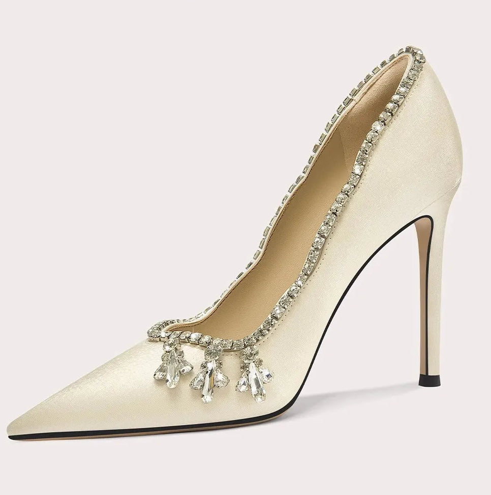 Beige high-heeled shoe with decorative elements on a white background