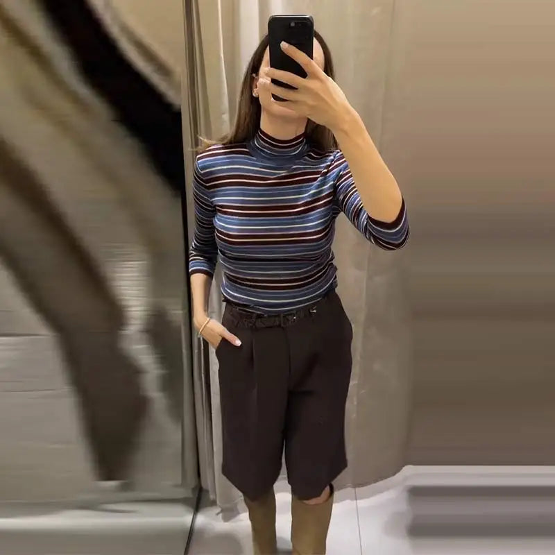 Person taking a mirror selfie wearing a striped turtleneck and dark pants.