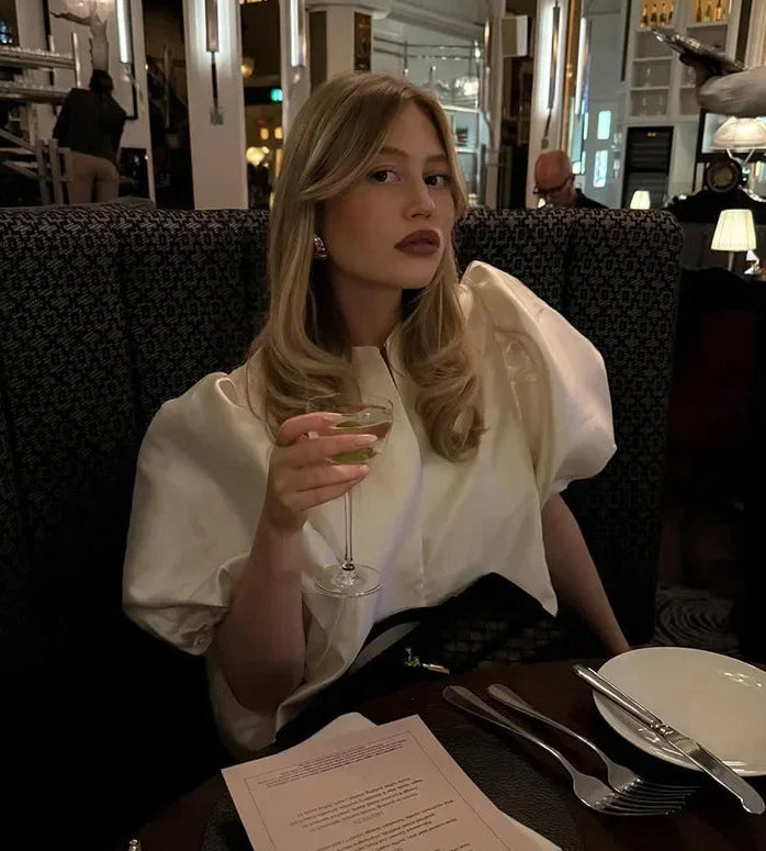 Woman sitting at a restaurant table holding a glass of wine.