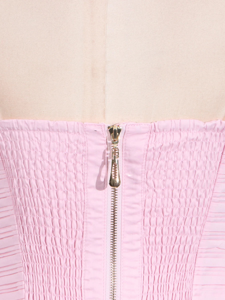 Close-up of a pink textured garment with a zipper on a beige background