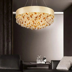 Gold chandelier hanging in a modern living room with dark walls and furniture.
