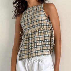 Person wearing a plaid sleeveless top and white pants against a plain background